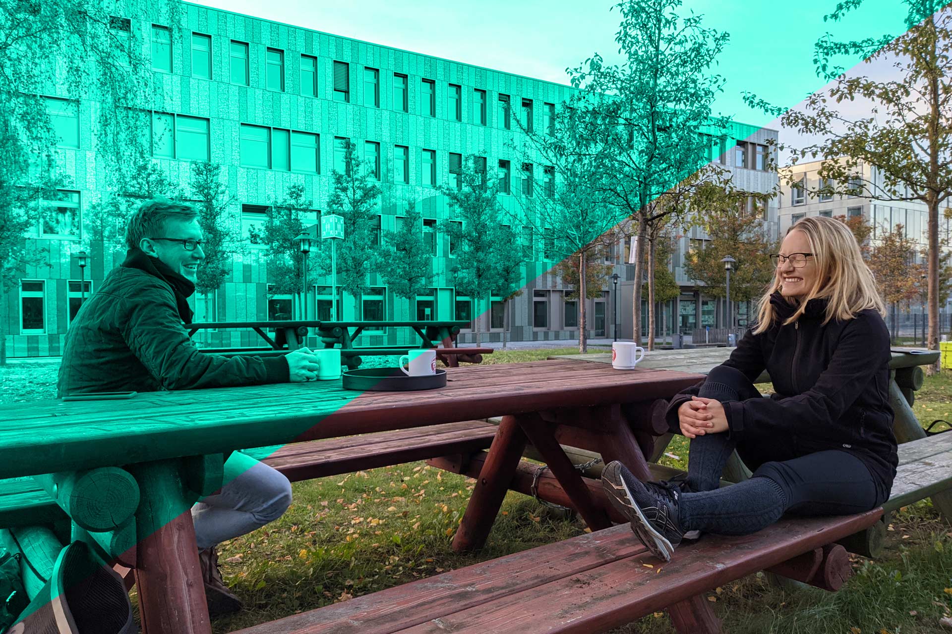 Christian und Sophia sitzen auf einer Bank auf der Campuswiese der FH Potsdam